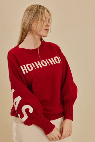Person wearing a red sweater with 'HO! HO! HO!' text on a beige background